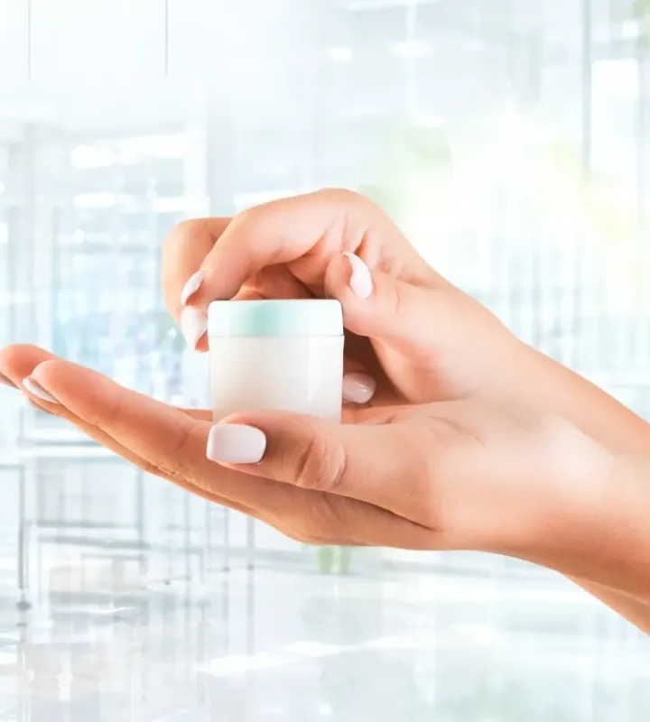 Hands holding a small cosmetic cream jar